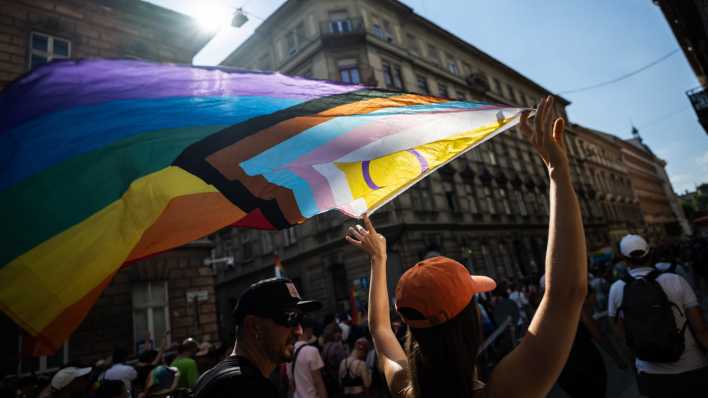 Eine Teilnehmerin hält bei einer Parade in Budapest eine Pride-Flagge in die Höhe.