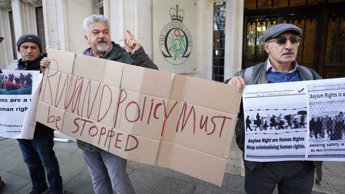 Protestierende vor dem Supreme Court in Großbritannien mit einem Schild "Ruanda-Politik muss beendet werden"